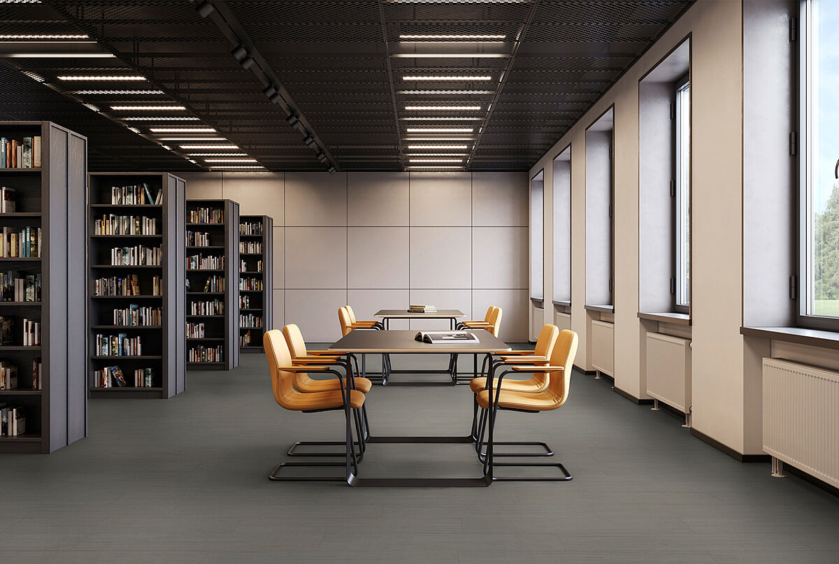 Library room with bookshelves, tables and yellow chairs on recycled elastic flooring with a modern dark grey texture.