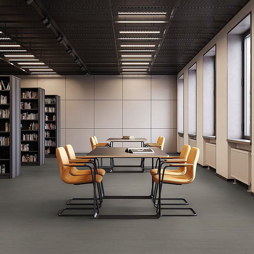 Library room with bookshelves, tables and yellow chairs on recycled elastic flooring with a modern dark grey texture.