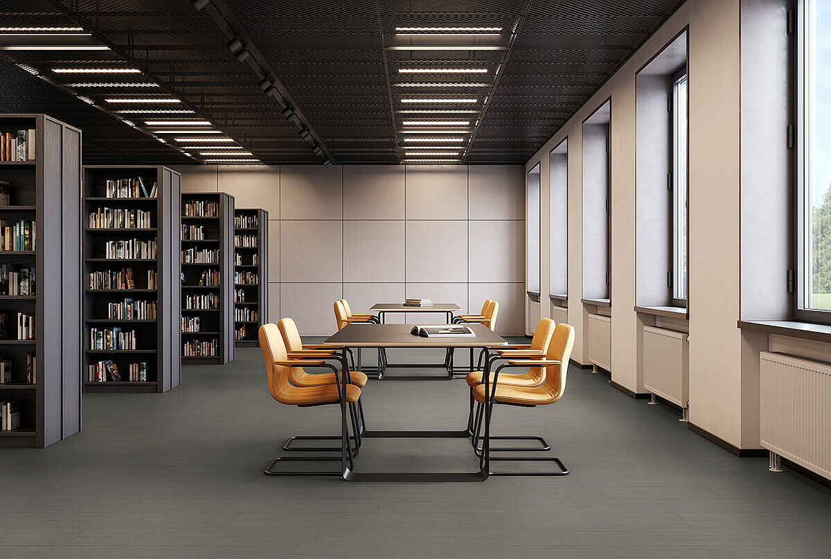 Library room with bookshelves, tables and yellow chairs on recycled elastic flooring with a modern dark grey texture.