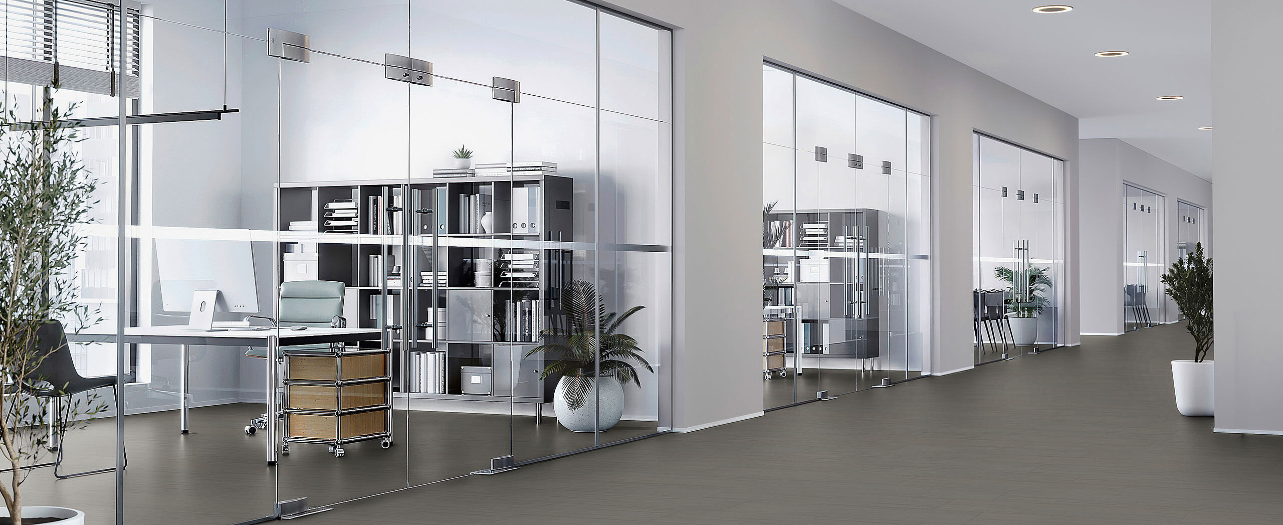 Recycled elastic flooring in elegant dark grey for modern offices – durable, easy to maintain and sustainable. Modern office with glass walls and workstations, recycled elastic flooring in a dark grey finish with a calm matte surface.